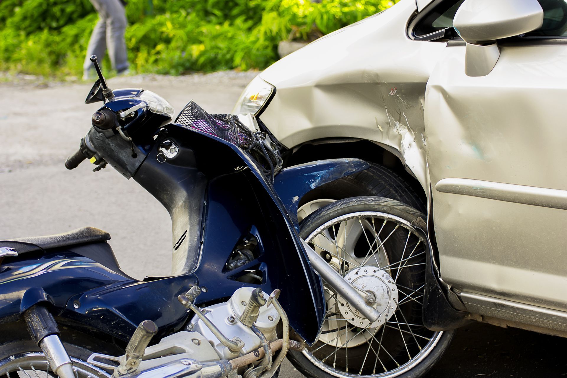 Damaged motorcycle and car after a collision on a road.