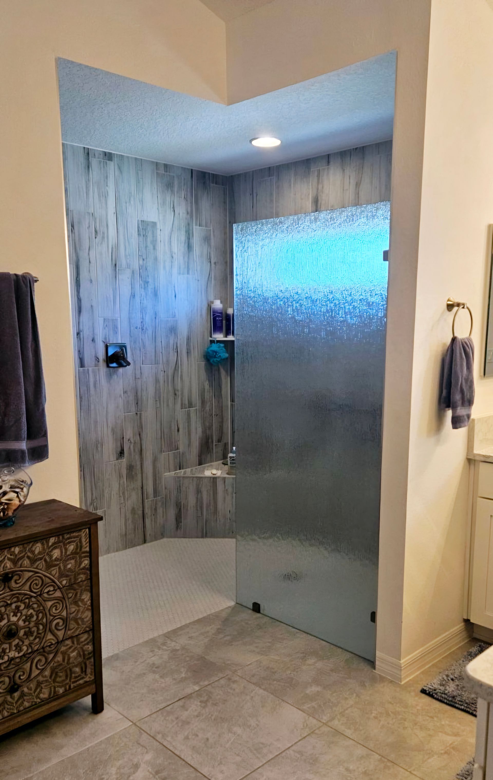 A bathroom with a walk in shower and a window.