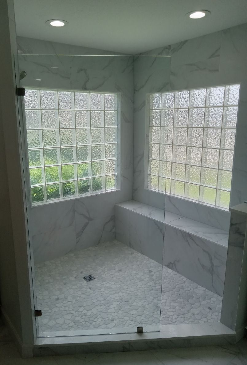 A bathroom with a walk in shower with a glass door.