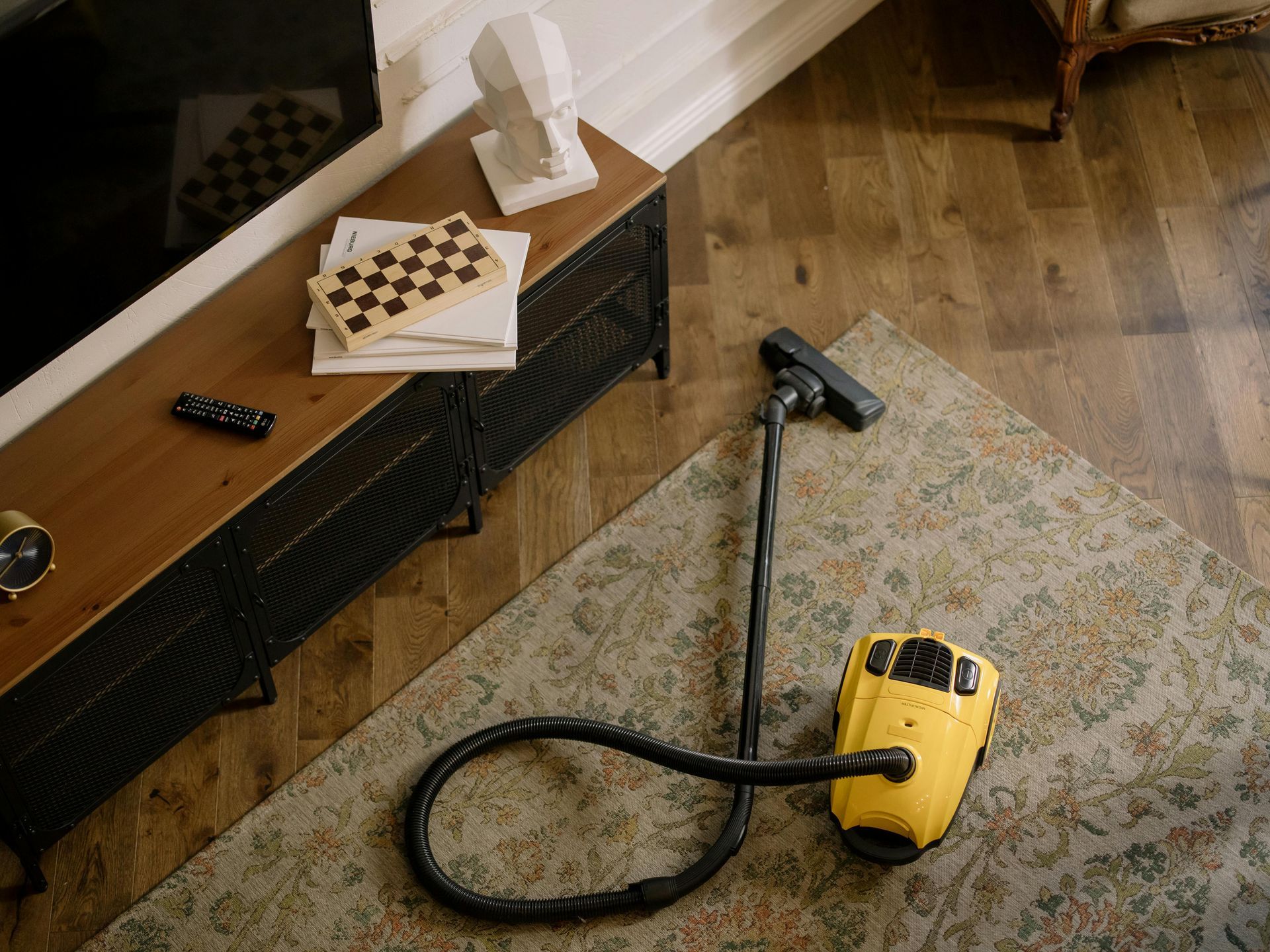 A yellow vacuum cleaner is sitting on a rug in a living room.