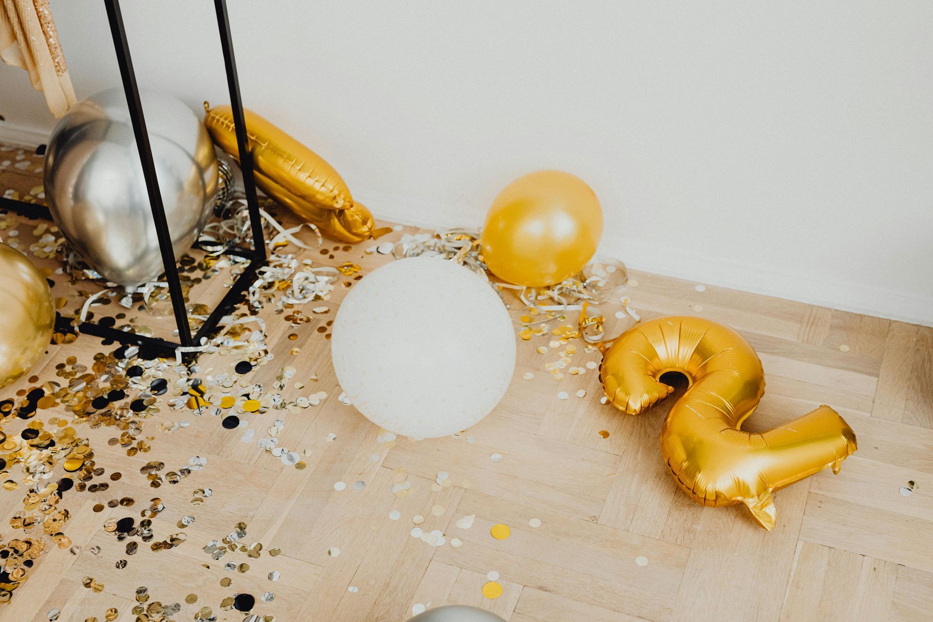 A messy room with balloons and confetti on the floor.