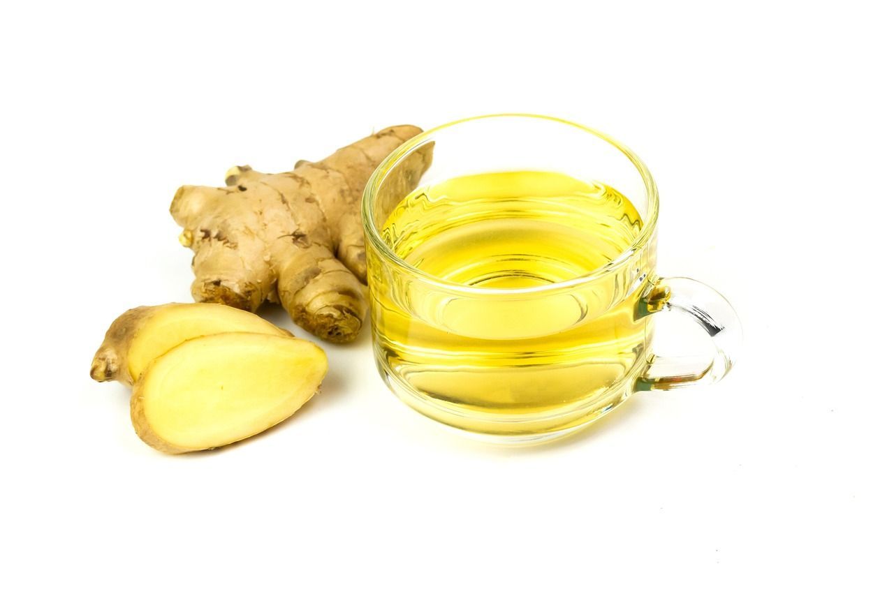 Ginger root and a glass of ginger tea on a white background.