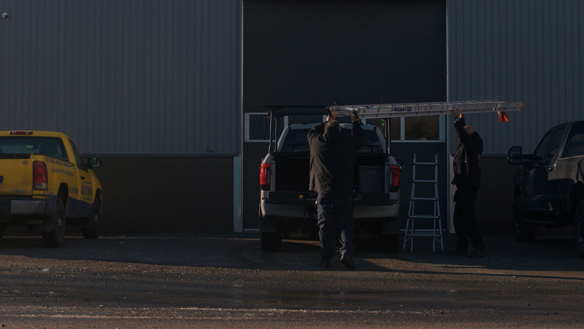 Un homme met une échelle à l'arrière d'un camion.