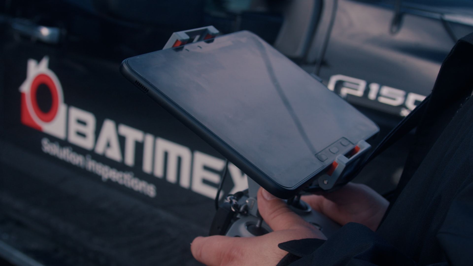Une personne tient une télécommande devant un camion batimex