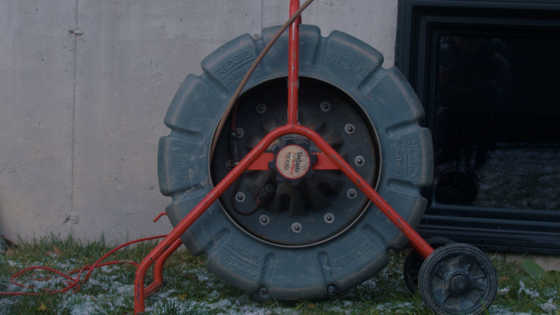 Une caméra de drainage est posée sur l'herbe devant un bâtiment.