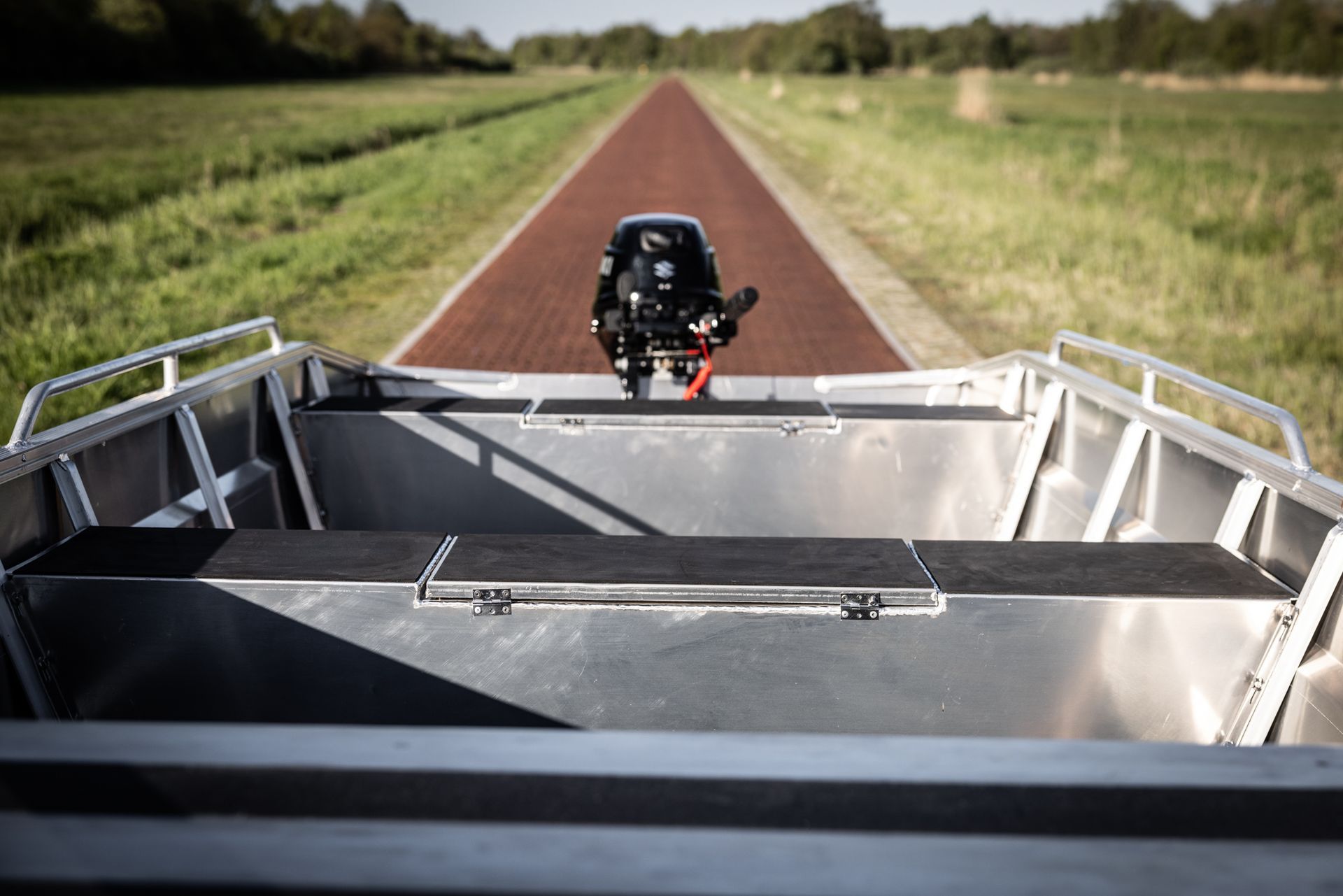 Een boot met een motor achterop staat langs de kant van de weg geparkeerd.