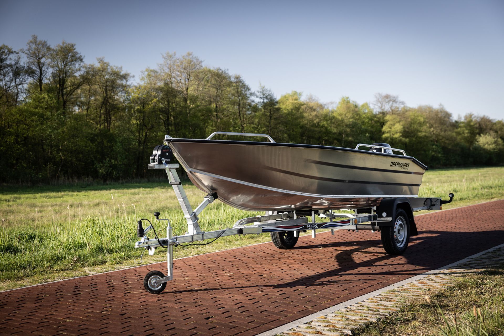 Een boot ligt op een trailer op een stenen weg.