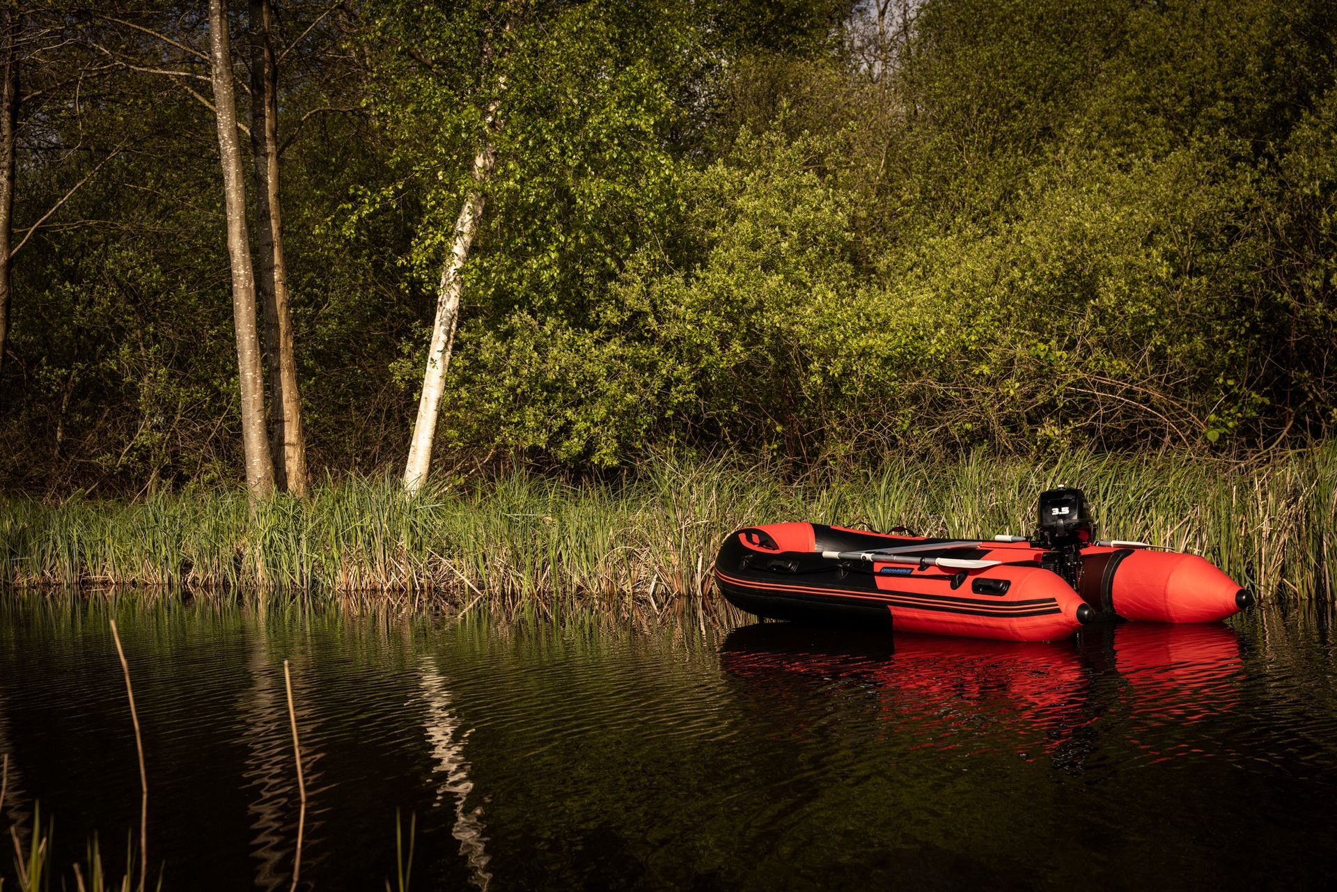 Een rood vlot drijft op een meer omgeven door bomen.