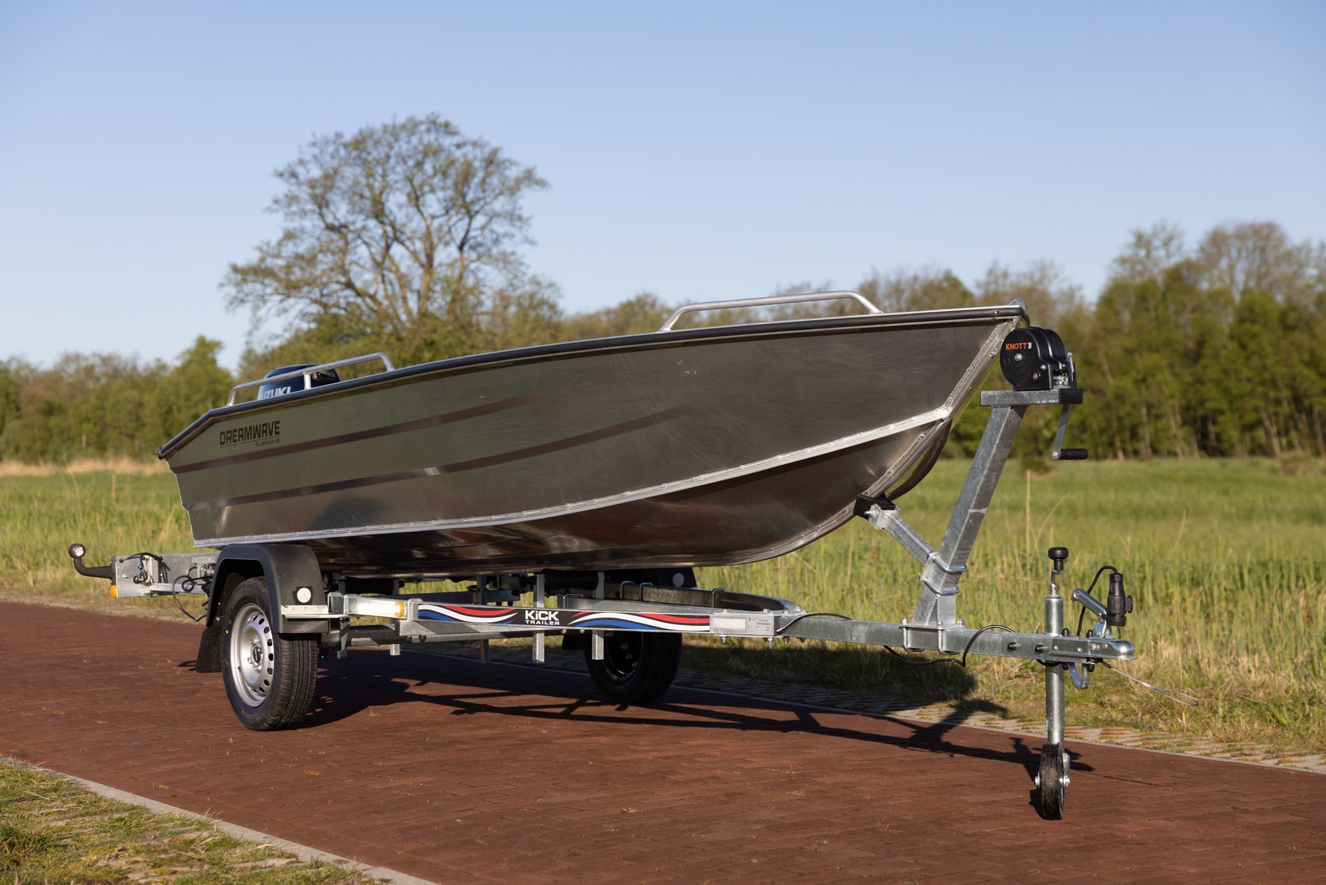 Een boot ligt op een trailer in een veld.
