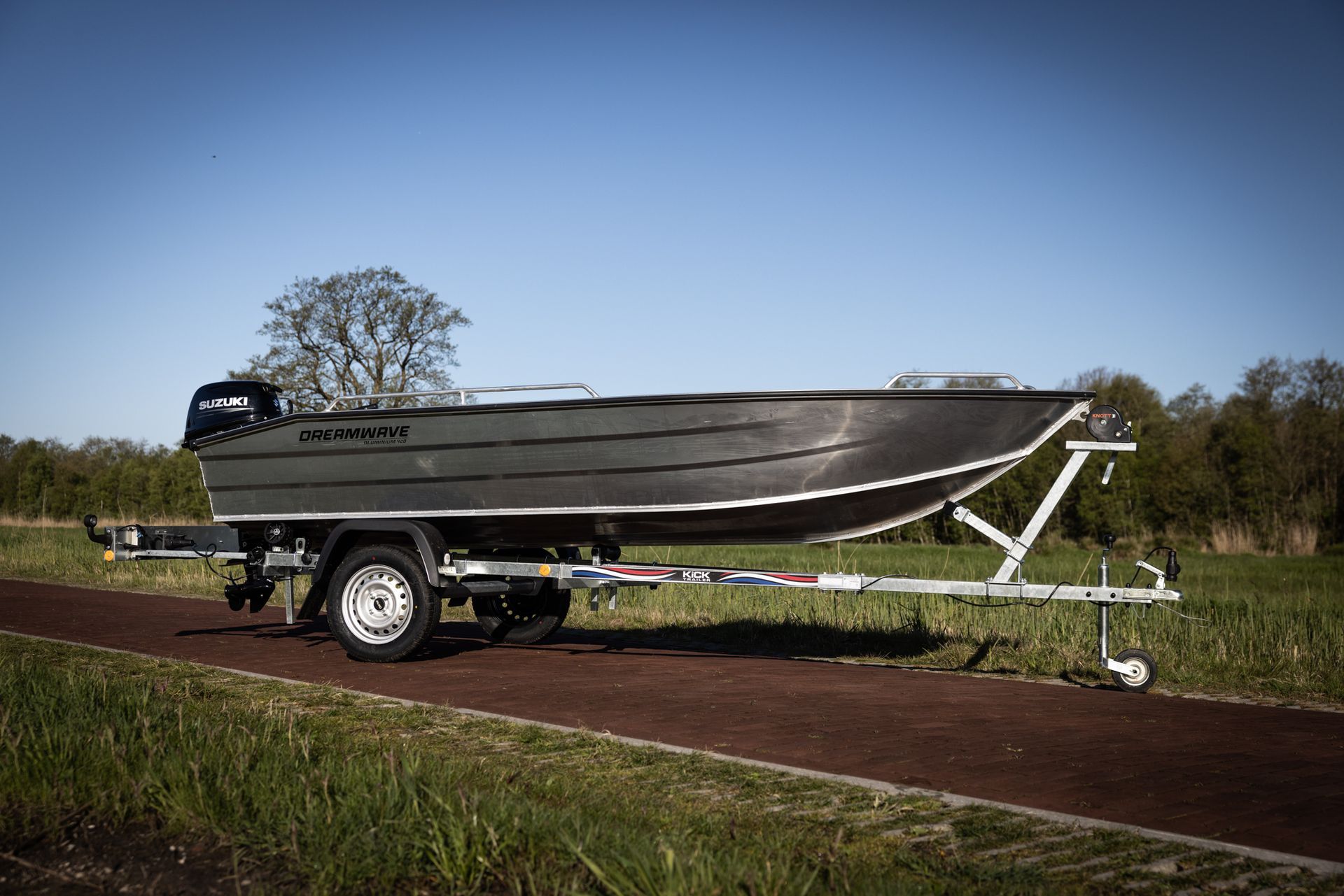 Een boot ligt op een trailer in een veld.