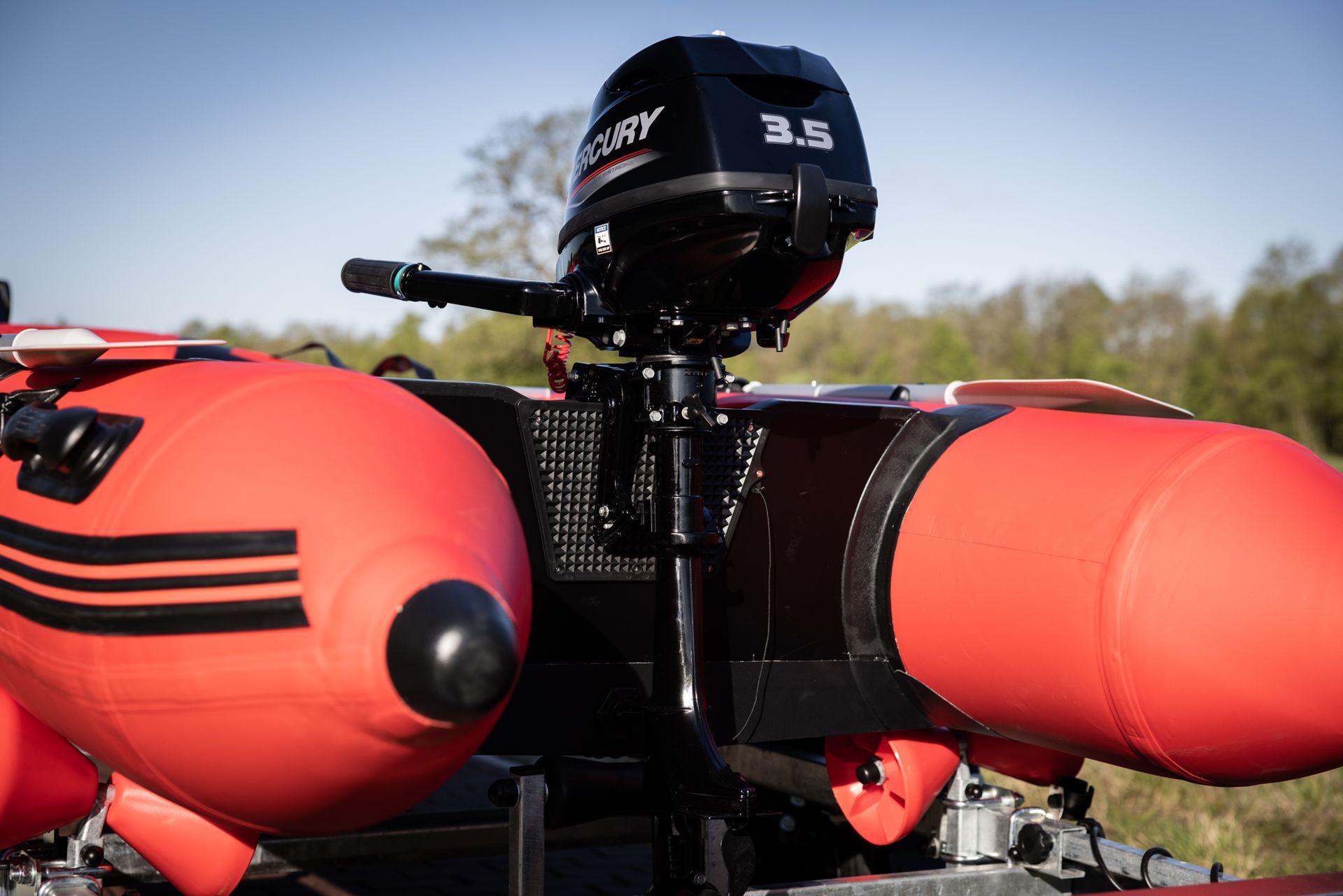 Een rode boot met daaraan een Mercury buitenboordmotor.