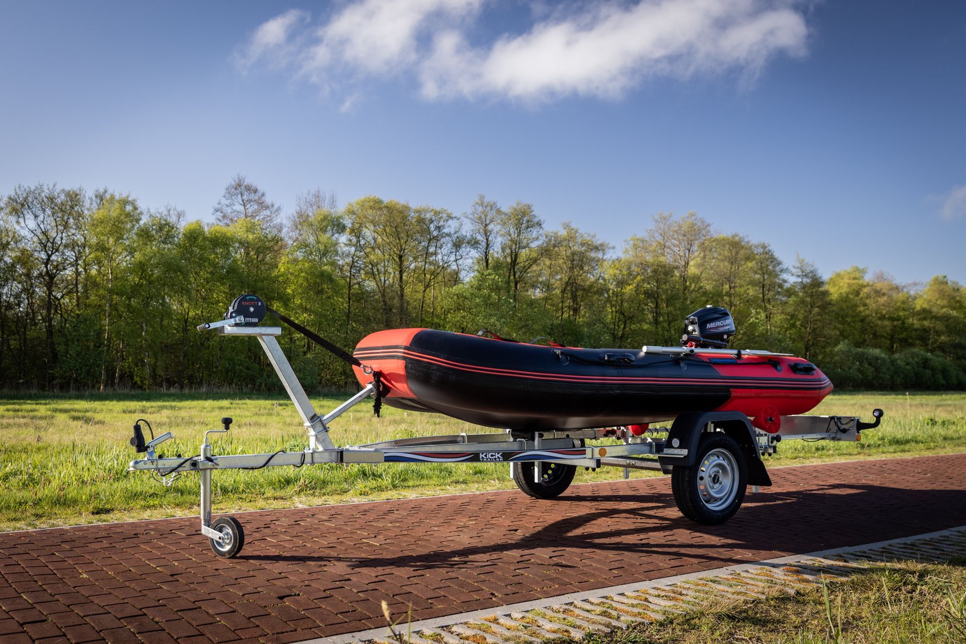 Een rood-zwarte boot staat op een trailer.
