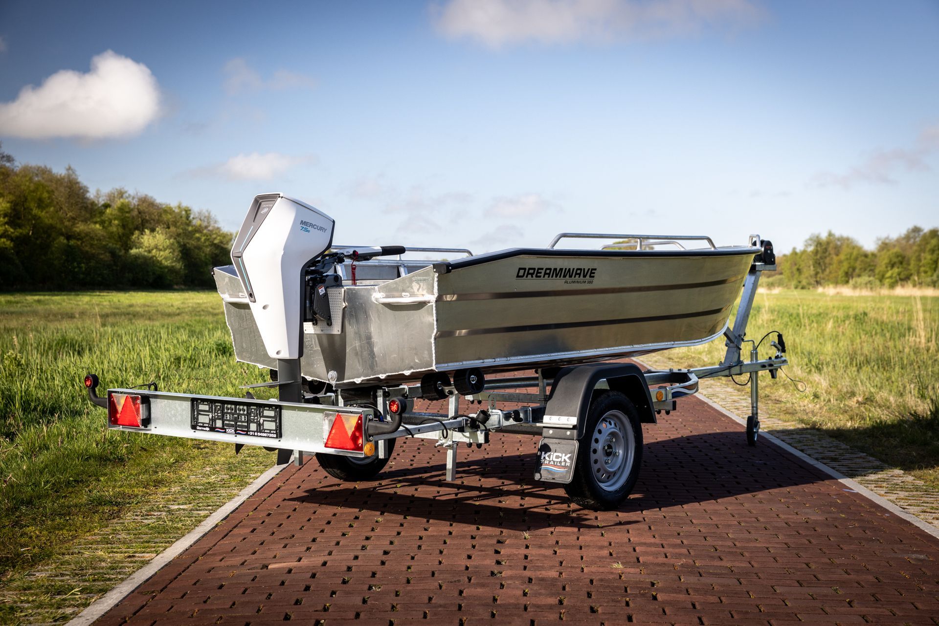 Een boot staat op een trailer op een stenen weg.