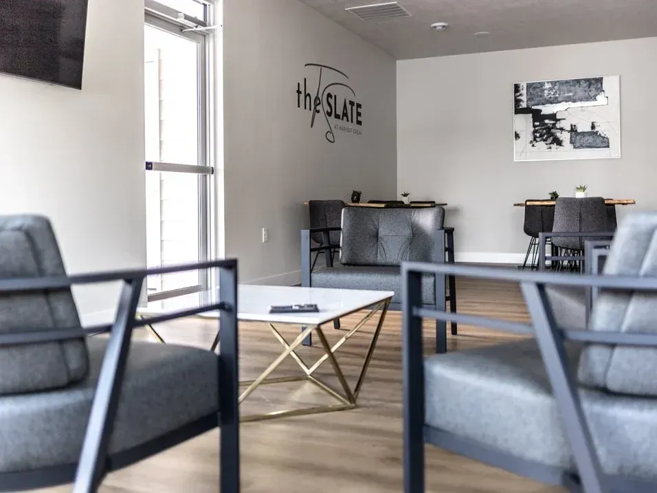 The Slate clubhouse with chairs a coffee table and a sign that says The Slate