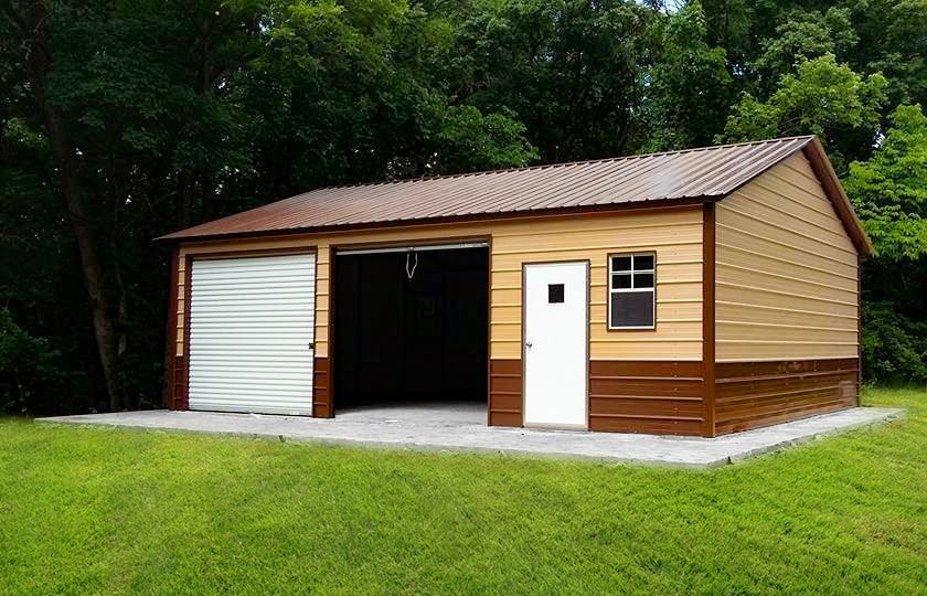 Tan shed with gray doors and roof, in a backyard setting near a wooden fence and green trees.