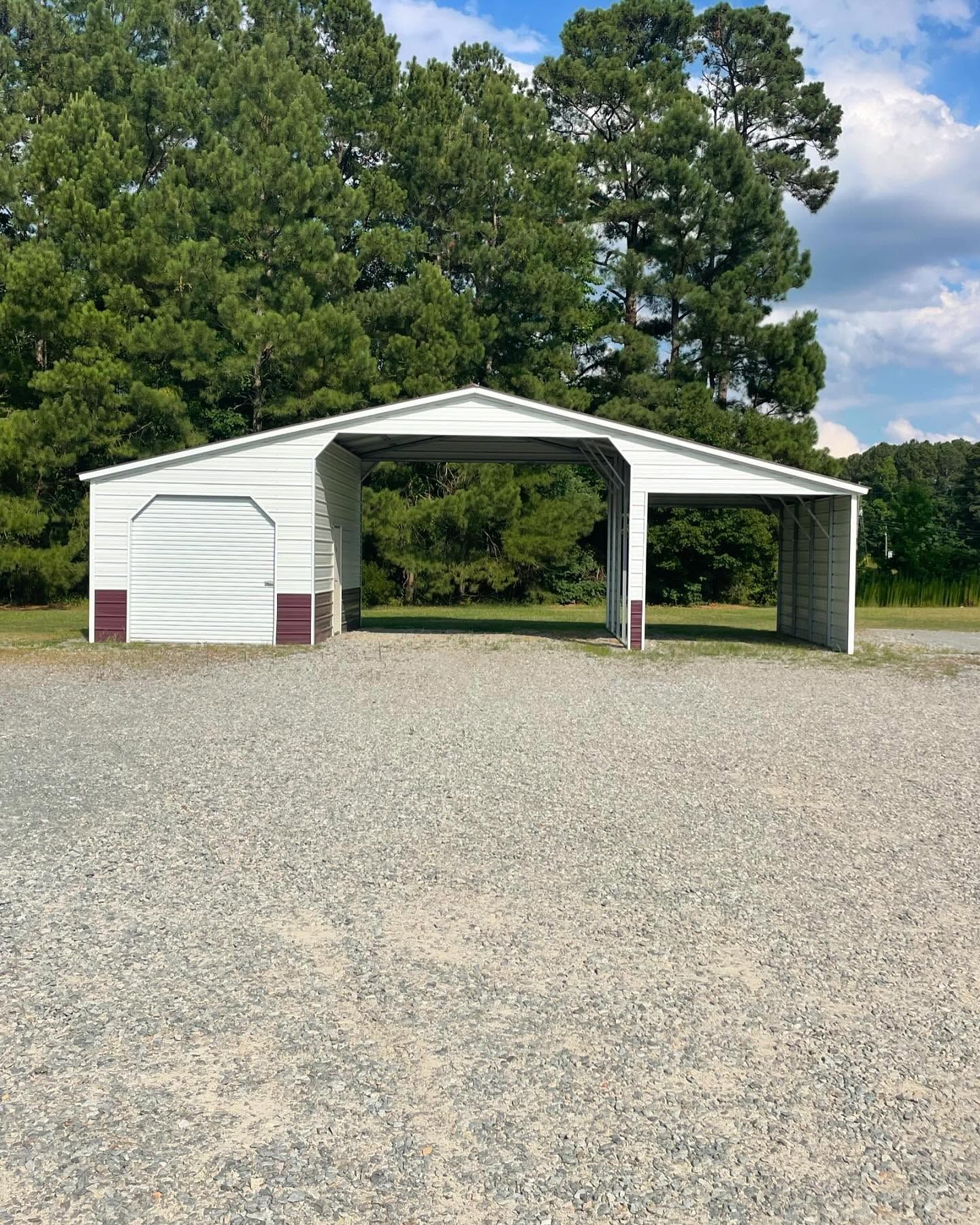 White metal carport with open sides, gravel ground, trees in background.