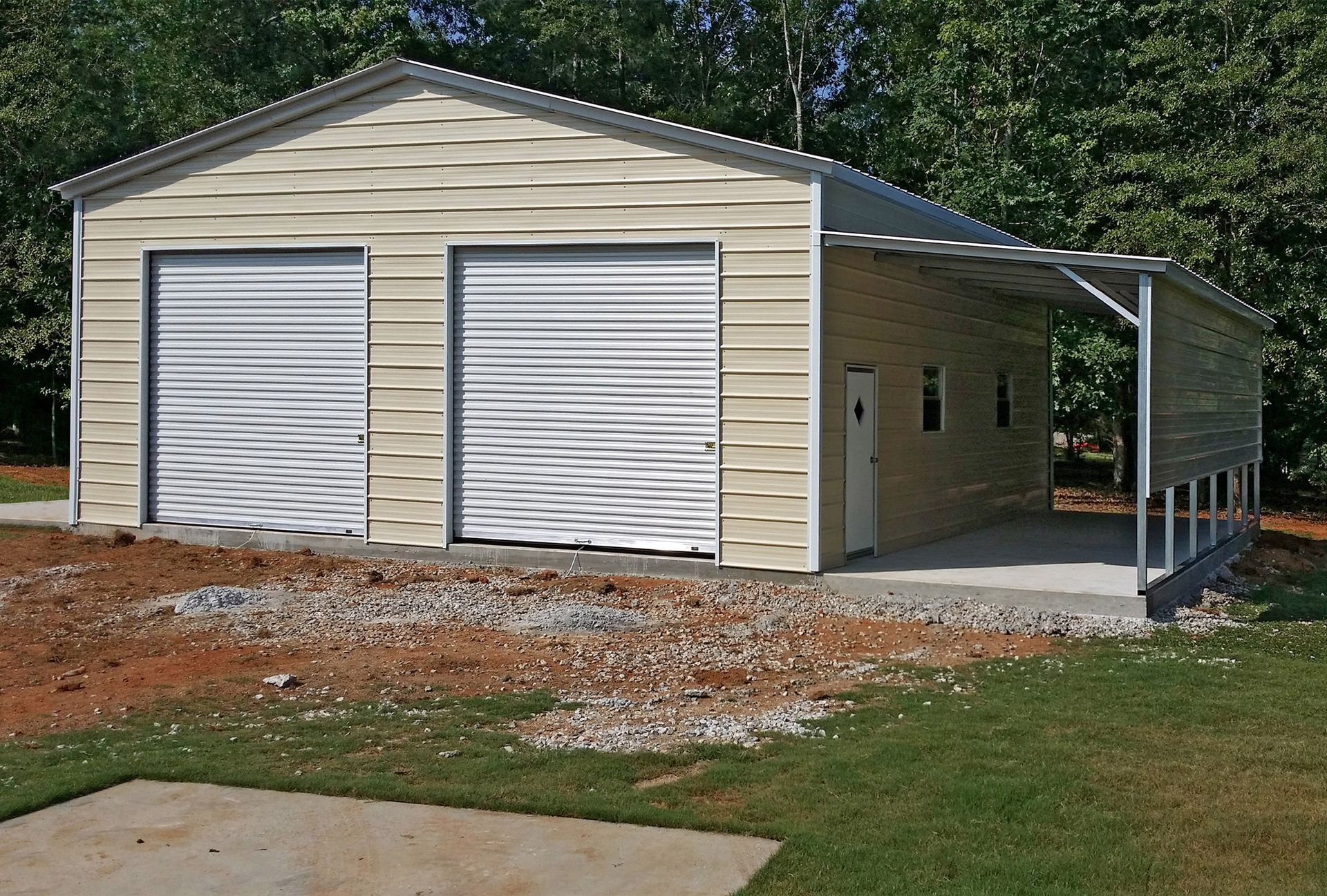 Tan metal garage with two roll-up doors, a lean-to, and a concrete pad.