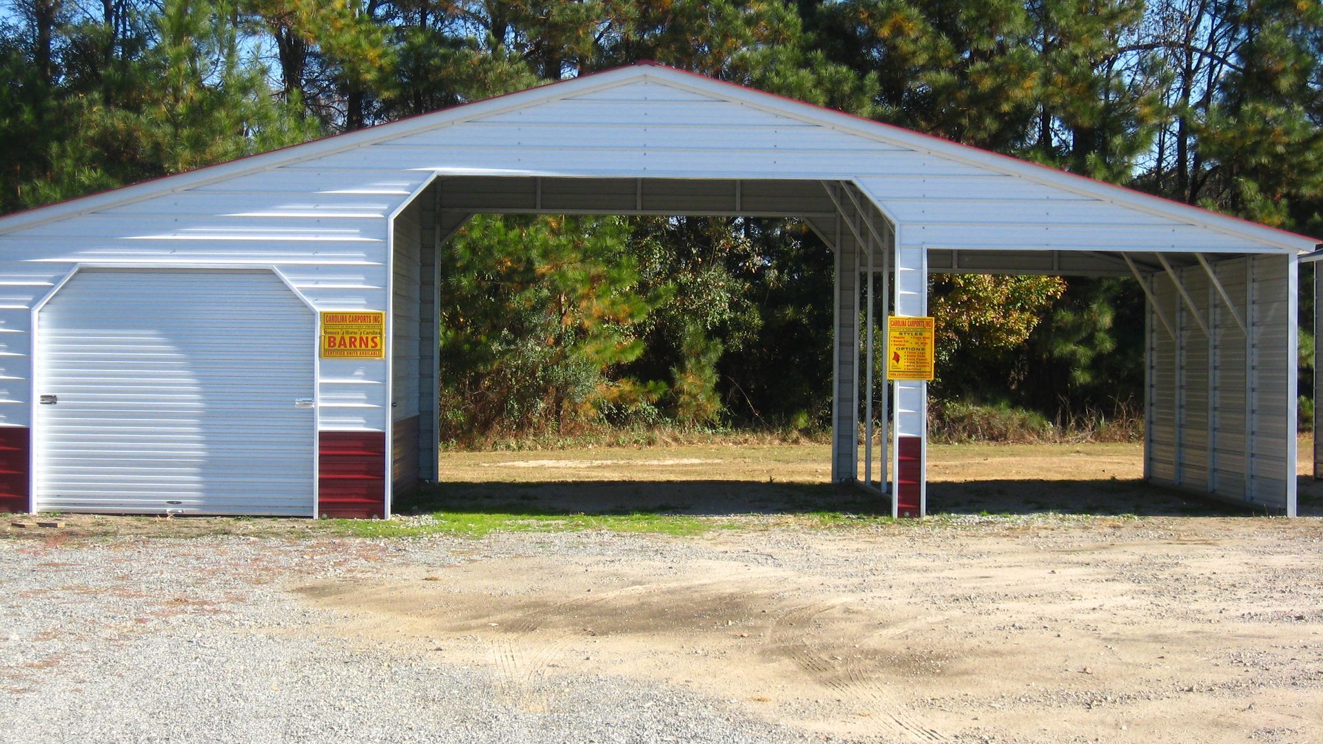 Metal garage with a closed door on the left and open bays. White, with red trim. Outdoors.