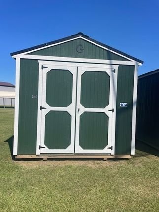 Tan storage shed with white trim, black hardware, and double doors outdoors.