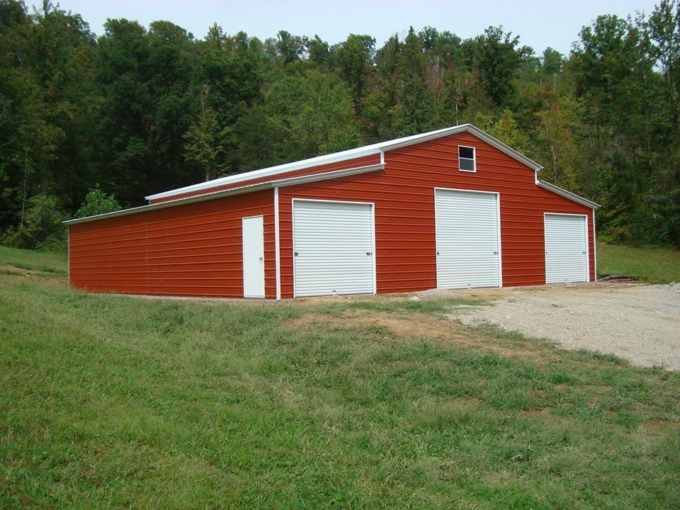 White shed with dark roof, brown door, and two windows on a grassy lot.