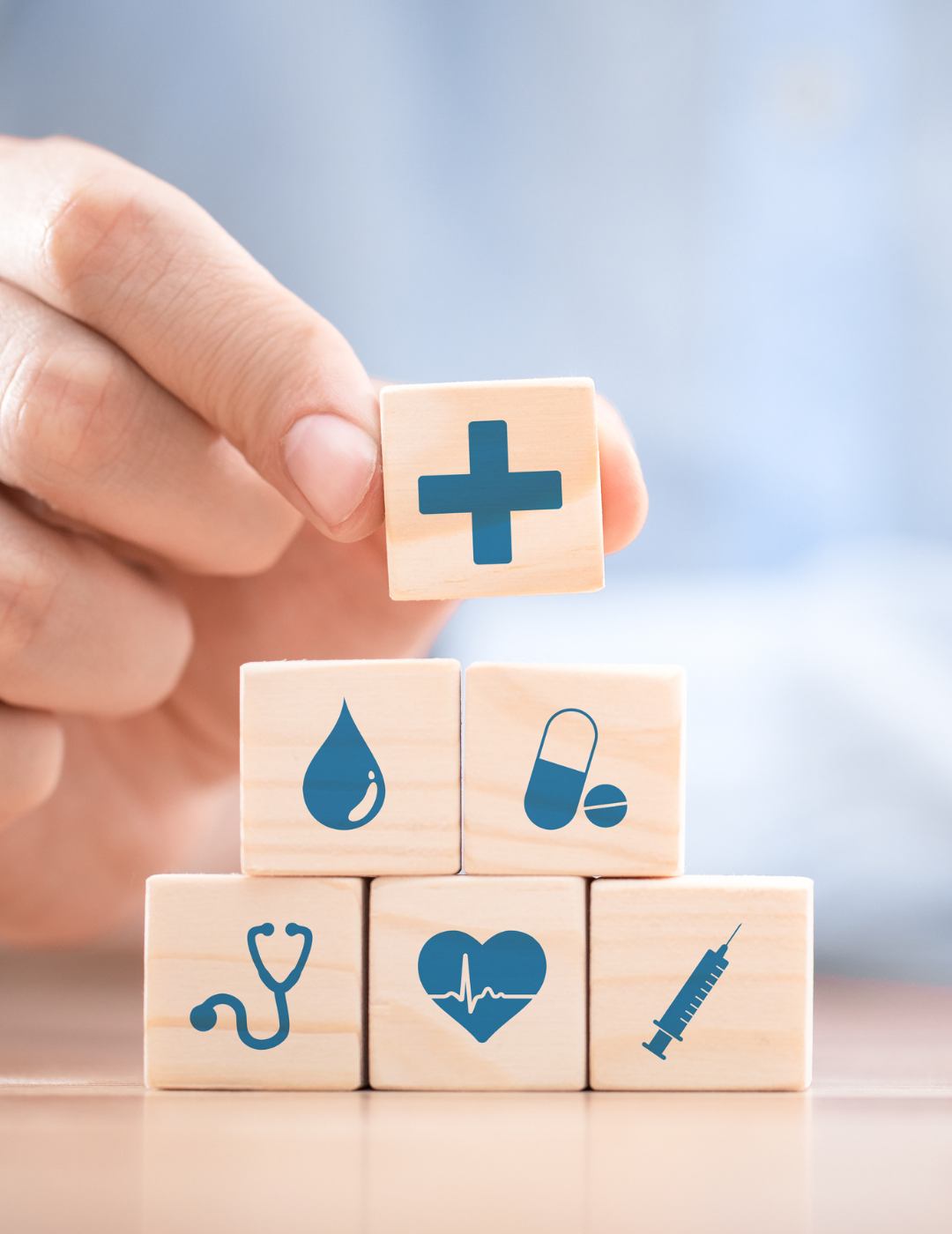 A person is stacking wooden blocks with medical icons on them.
