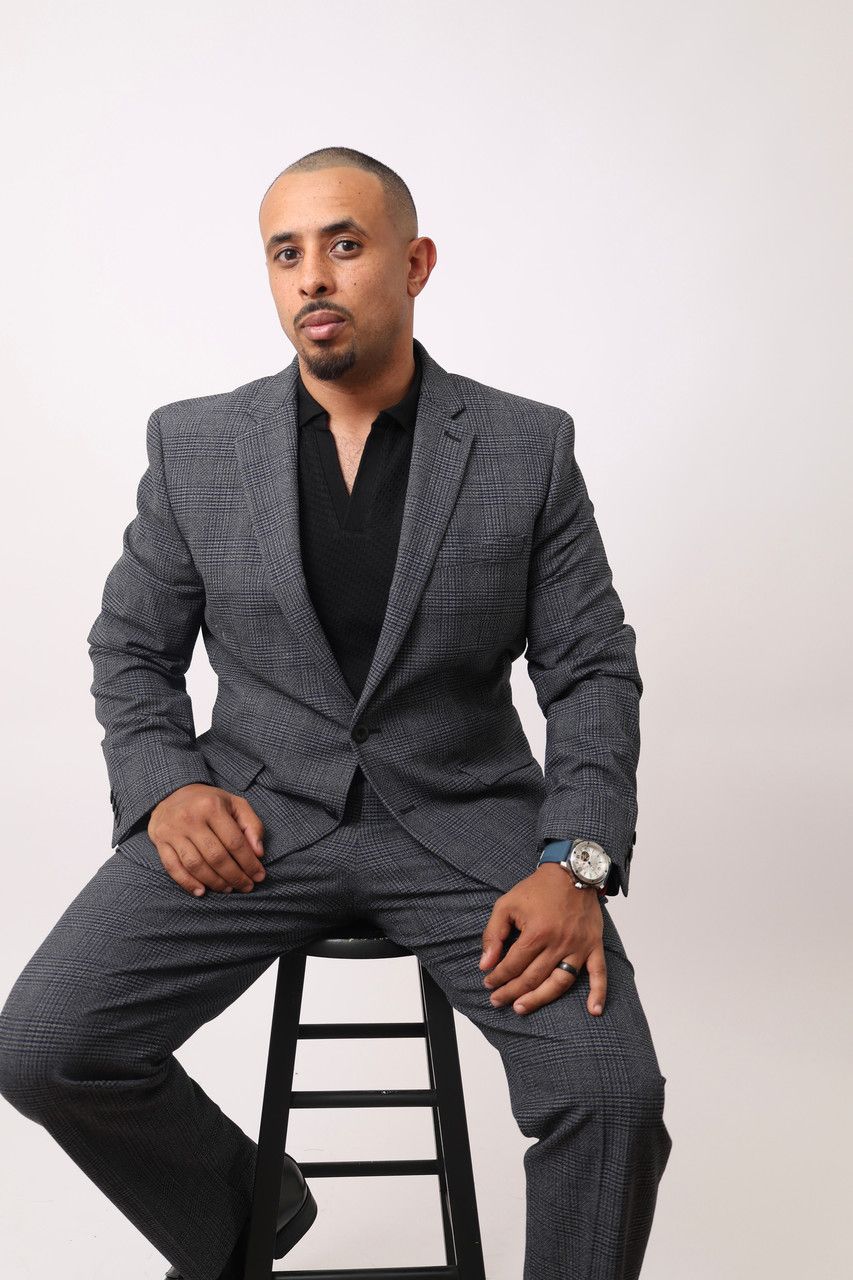 A man in a suit is sitting on a stool