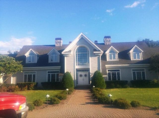 A large white house with a red truck parked in front of it