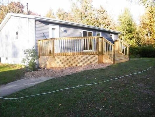 A mobile home with a large wooden deck in front of it.