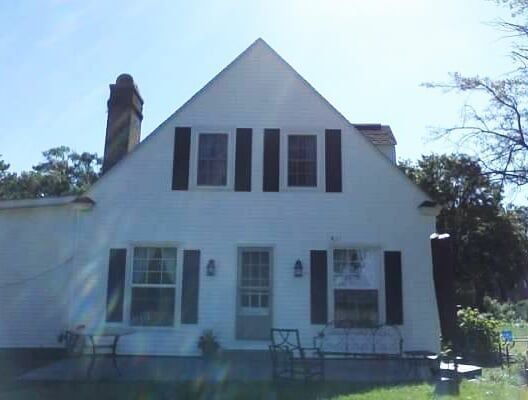 A white house with black shutters and a chimney