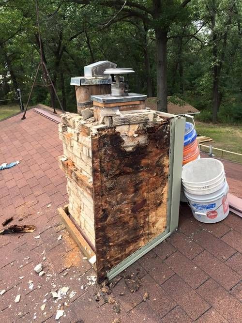 A brick chimney is sitting on top of a roof.