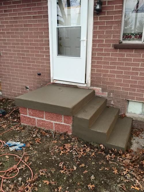 A brick house with concrete steps leading up to the front door.