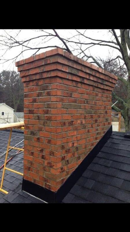 A brick chimney is sitting on top of a roof.