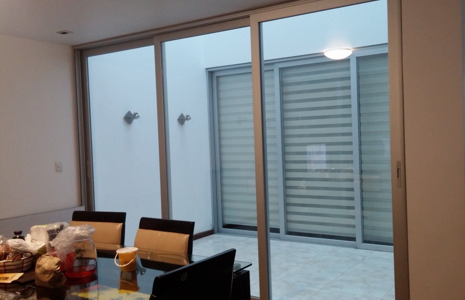 Un comedor con una pared de cristal que da a un pequeño patio con persianas.