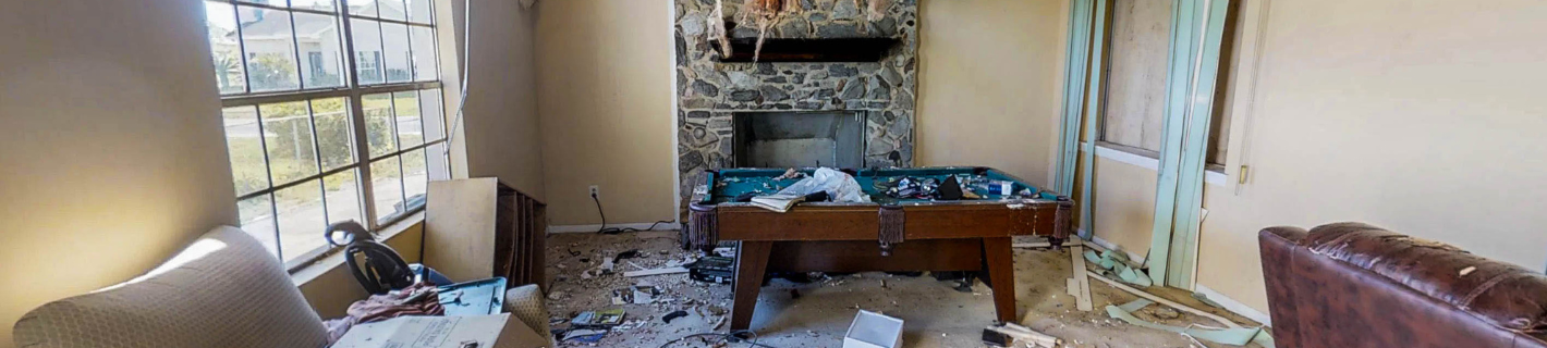 A room with a fireplace, a foosball table, and a window. The room looks damaged.