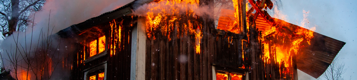 A house engulfed in flames, bright orange fire and smoke billowing.