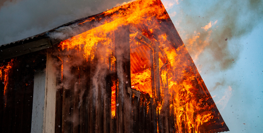 Burning wooden structure with flames and smoke.