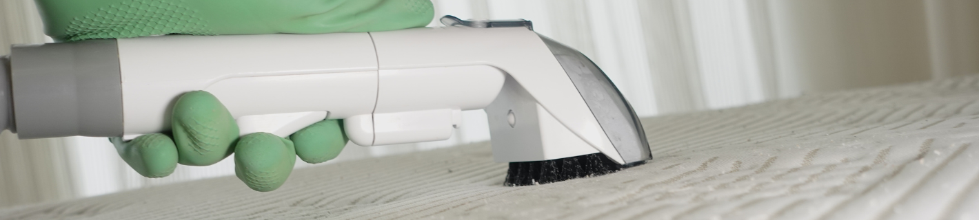 A handheld vacuum cleaner with a brush attachment cleaning a white, textured surface.