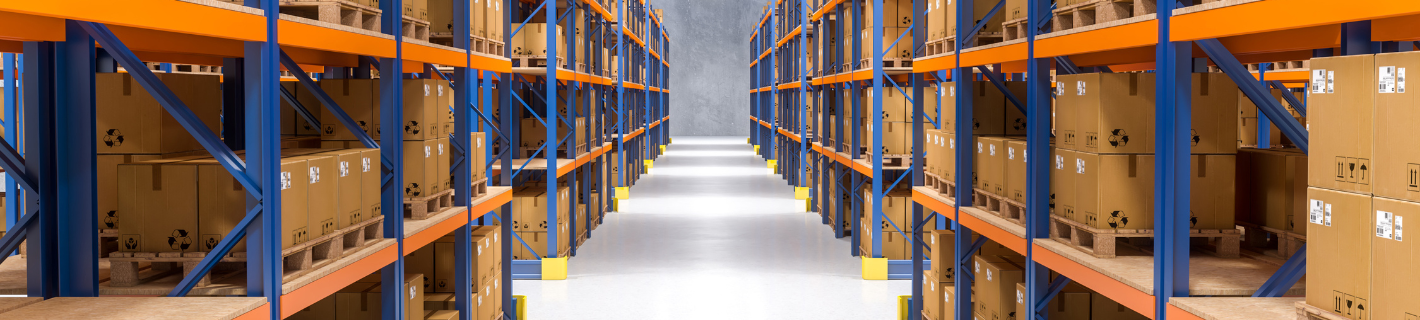 Warehouse interior with rows of storage racks filled with cardboard boxes.