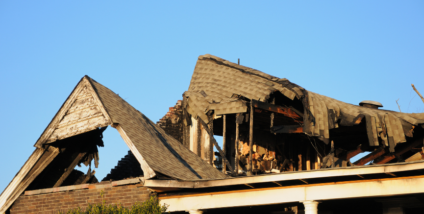 Burned roof of a house, sky in background.