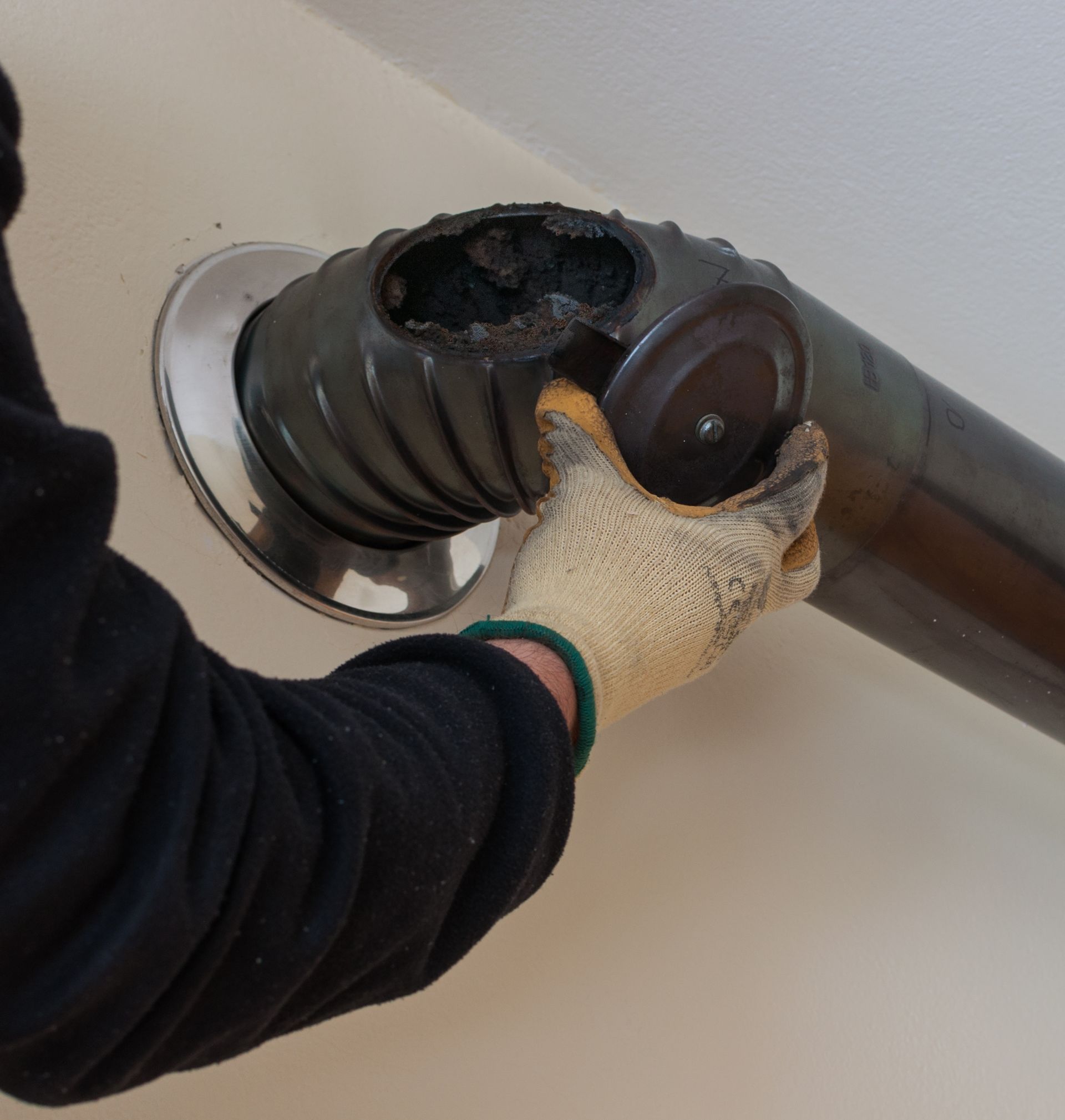 Person in gloves removing a cap from a damaged chimney pipe.