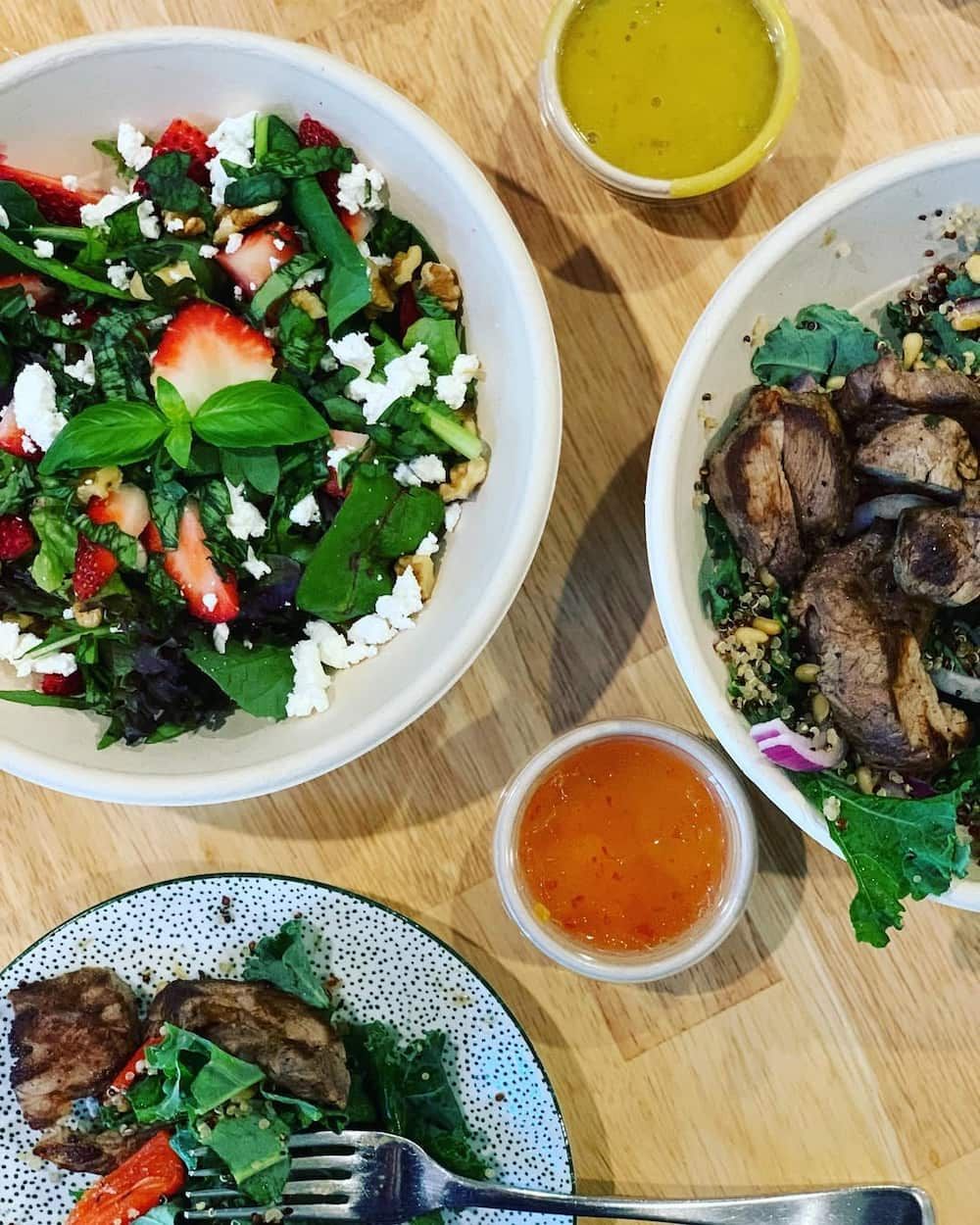 A Table Topped With Bowls of Food Including a Salad and a Plate of Meat — Swish Cafe in Ballina, NSW