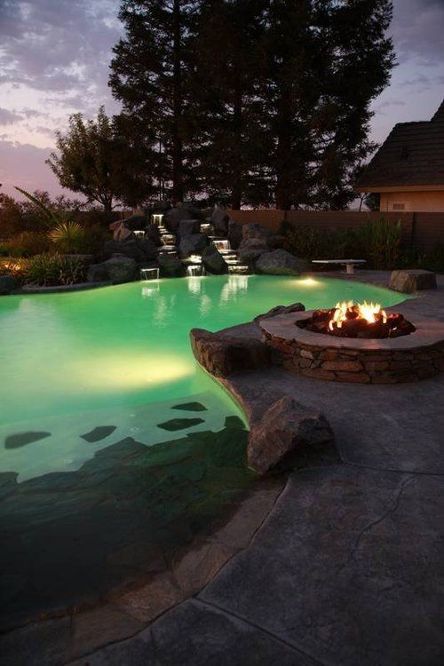 A swimming pool with a fire pit in the middle of it