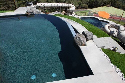 A large swimming pool with a water slide in the background
