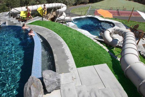 A man is swimming in a pool next to a water slide