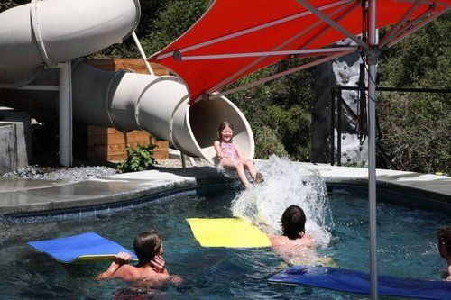 A little girl is sliding down a water slide in a swimming pool.