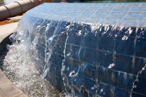 A waterfall is coming down a blue tiled wall