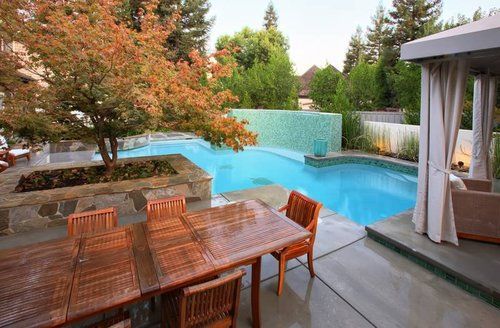 A large swimming pool with a table and chairs in front of it