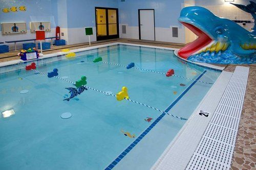 A large indoor swimming pool with a whale statue in the middle