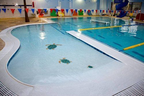 A large indoor swimming pool with a slide in the background