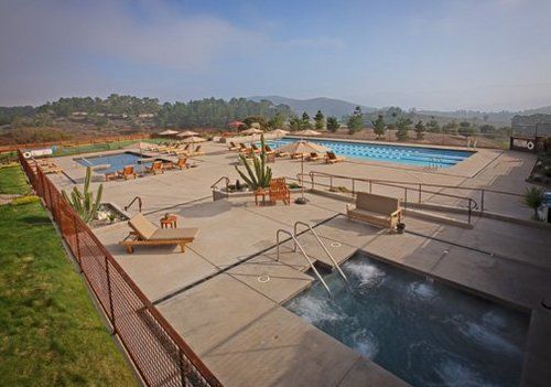 A large swimming pool with a hot tub in the middle of it